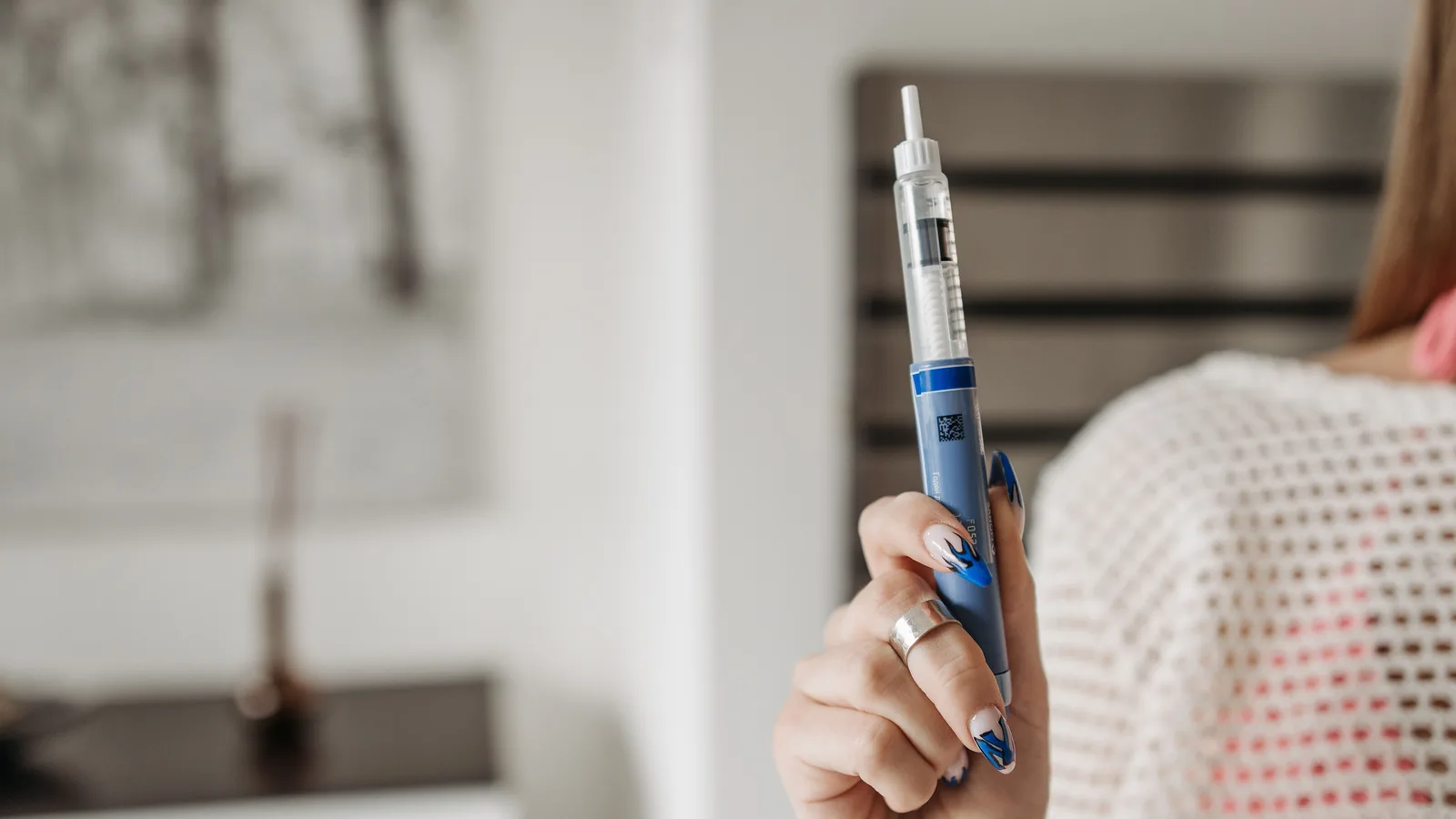 Hand holding a medication injection pen at home