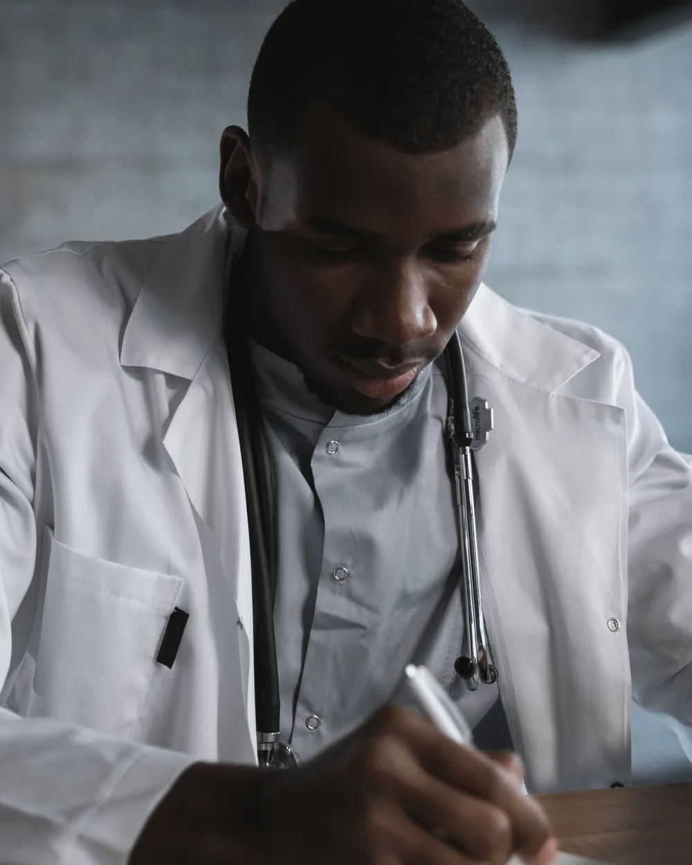 Clinician writing notes with a stethoscope visible